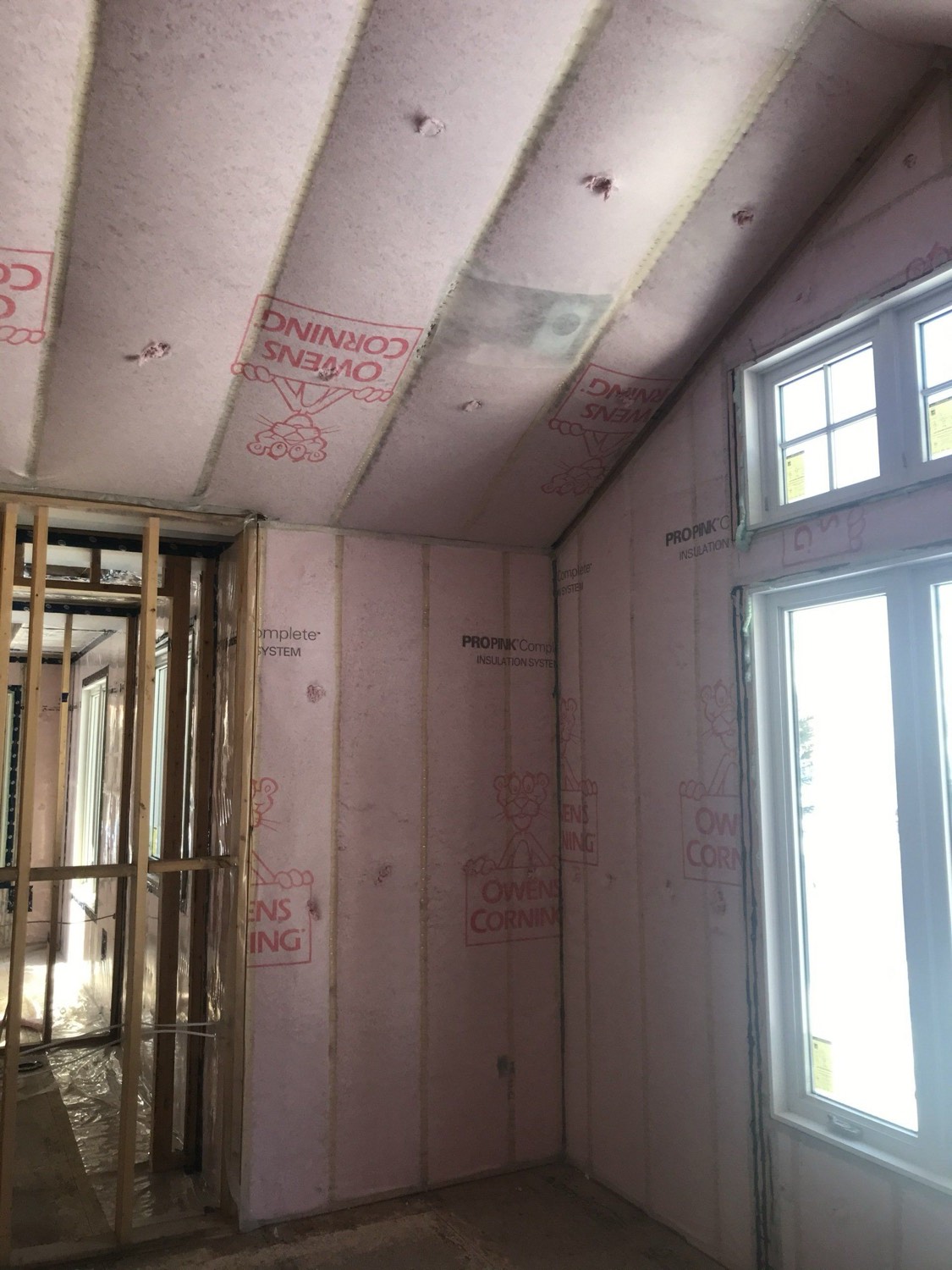 Batt insulation fitted between the studs and rafters of a home under construction