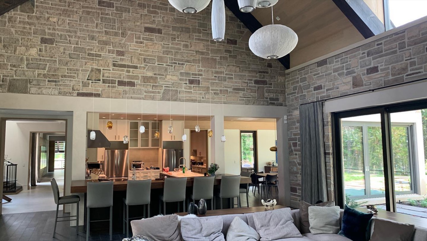 Open kitchen and great room with a stone wall, cathedral ceiling and exposed beams