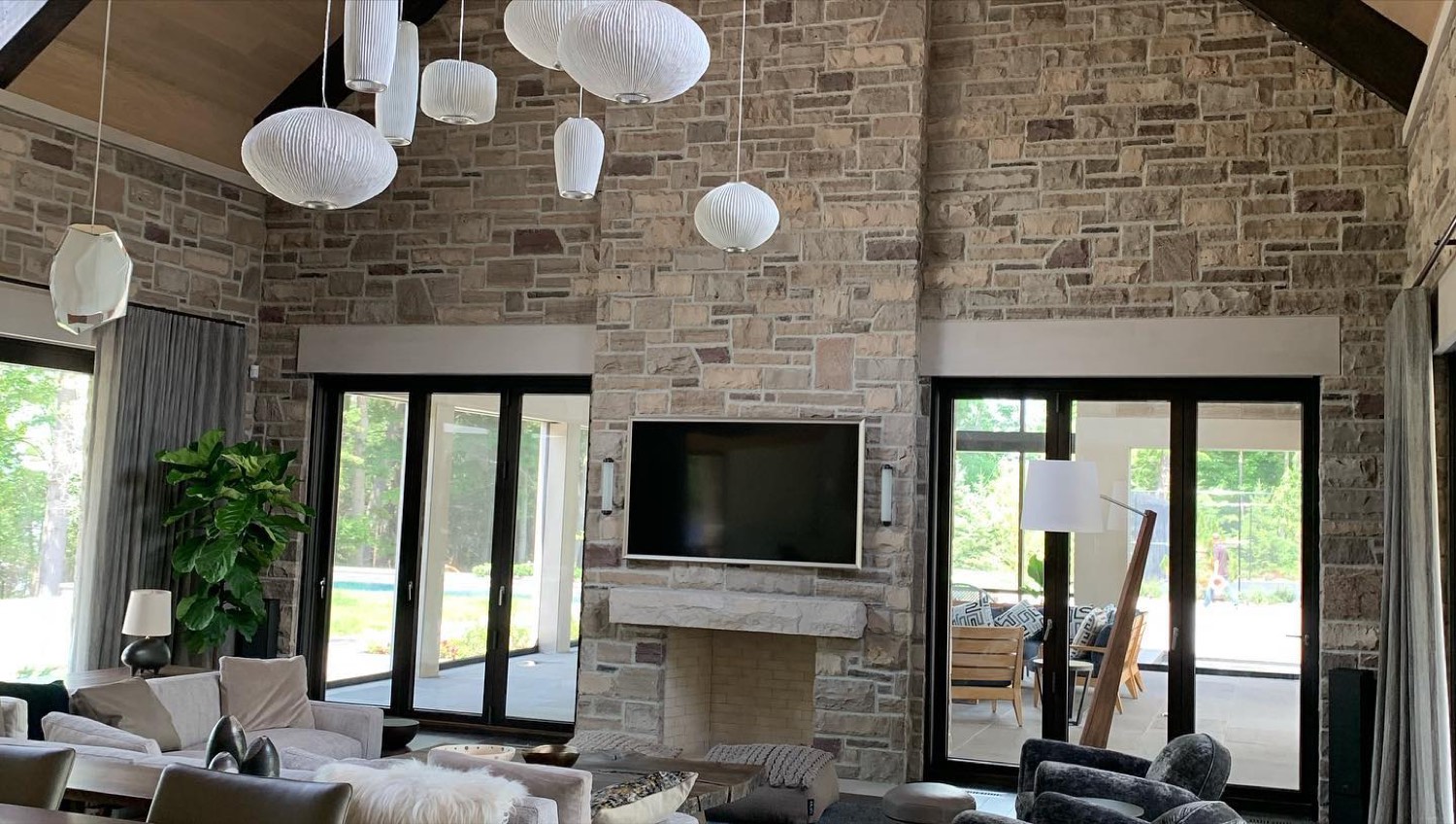 Great room with a full-height stone fireplace wall and sliding glass doors to a pool deck