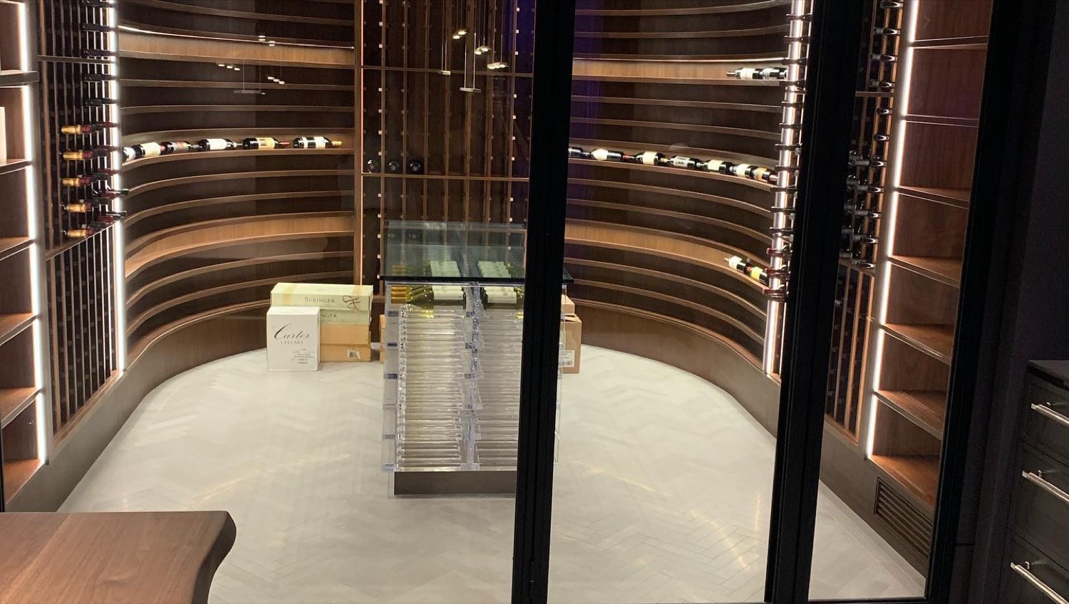 Custom curved wine cellar with backlit racking behind a glass wall
